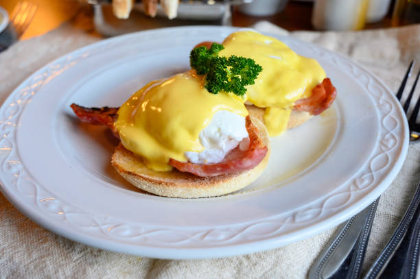 istock Weekend brunch in Scotland with two eggs benedict on homemade muffuns with roasted bacon and yellow hollandaise sauce. 1200949181