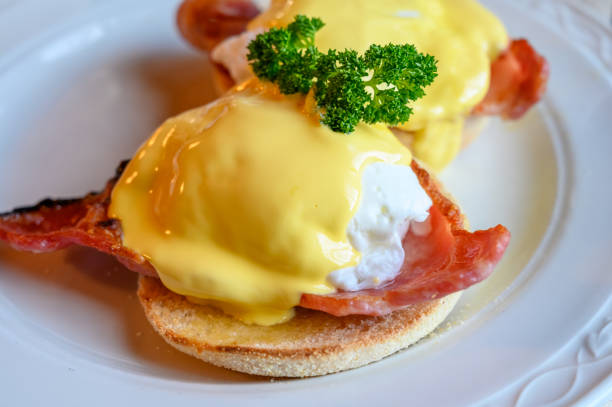 istock Weekend brunch in Scotland with two eggs benedict on homemade muffuns with roasted bacon and yellow hollandaise sauce. 1200949211