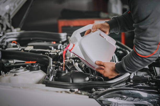 Filling the water tank with antifreeze in the engine compartment of a car stock photo