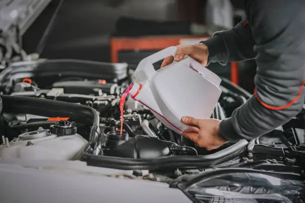 Photo of Filling the water tank with antifreeze in the engine compartment of a car