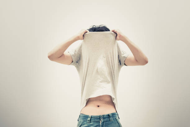 hombre quitándose una camiseta (material de imagen / concepto) - undressing fotografías e imágenes de stock