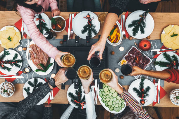 dinig de famille à la table en bois avec le gril de raclette - refreshment dinner table vegetable photos et images de collection