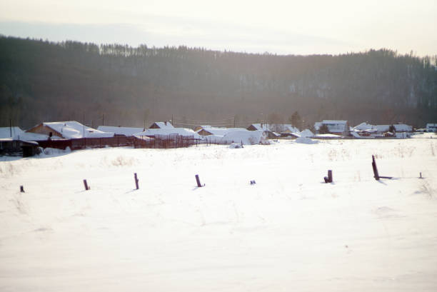 Snow covered village houses and field in the afternoon.
