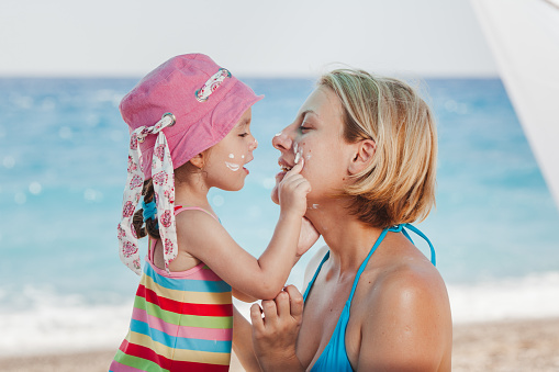 Mother and daughter applying suntan lotion on the beach