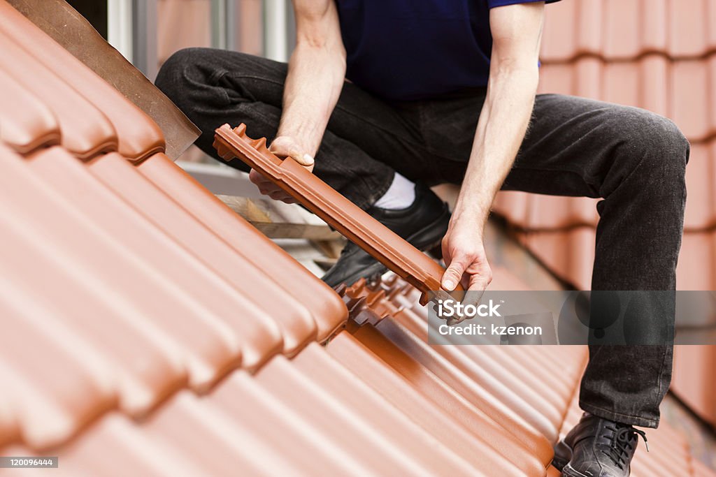 Tiler covering roof with new tile Roofing - construction worker standing on a roof covering it with tiles Rooftop Stock Photo