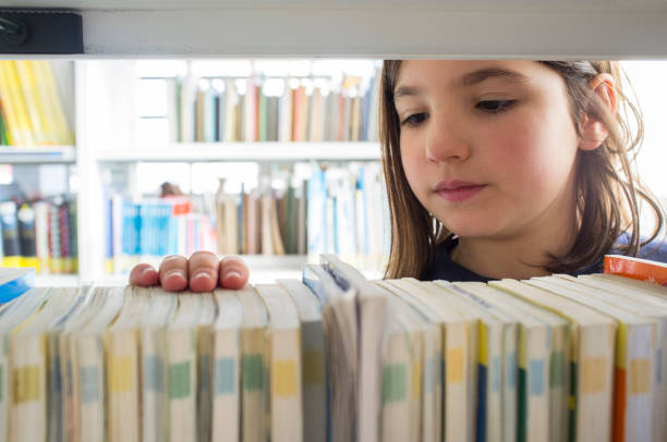 istock Young girl selecting books from library bookshelf 1200967167