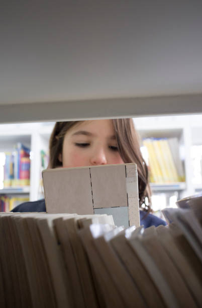 istock Young girl selecting books from library bookshelf 1200967171