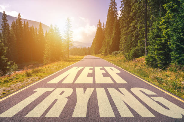 istock Keep trying written on road in the mountains. Keep trying text on the road. 1200967409