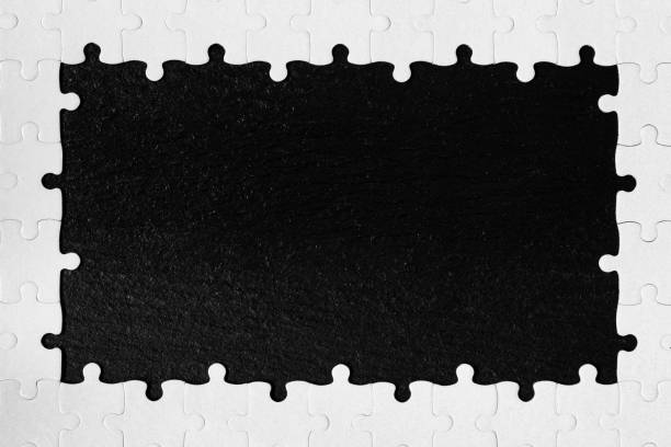 istock Framing in the form of a rectangle, made of a white jigsaw puzzle. Frame text and jigsaw puzzles. Frame made of jigsaw puzzle pieces on black background. 1200967454