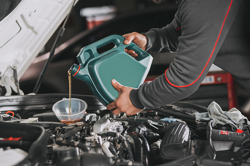 Pouring oil to car engine.