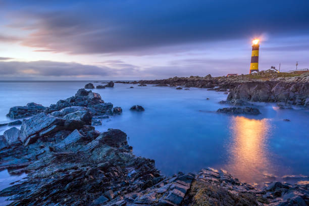 Twilight begins yielding to daylight at St. Johns Point Lighthouse Twilight begins yielding to daylight at St. Johns Point Lighthouse. Rocky coastline with blurred water and sky, long exposure photography lighthouse lighting equipment reflection rock stock pictures, royalty-free photos & images