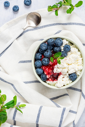 Cottage cheese with jam and fresh blueberries in a ceramic bowl top view, delicious and healthy breakfast.