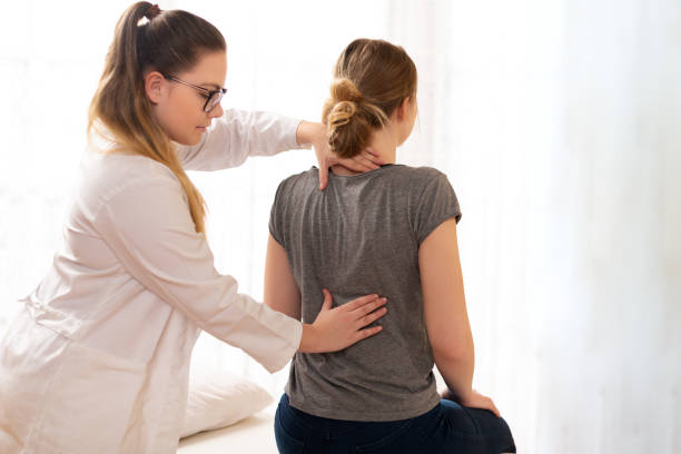 Female physiotherapist or a chiropractor examining patients back. Physiotherapy, rehabilitation concept. Female physiotherapist or a chiropractor examining patients back. Physiotherapy, rehabilitation concept. human back stock pictures, royalty-free photos & images