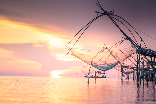 Sunrise at the fisherman village with silhouette of wooden fishing net yokyor and long tail wooden boat Pakpra, Pattalung, Thailand
