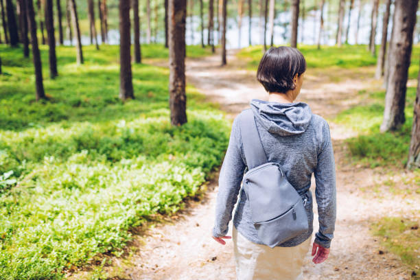 istock Woman with a small backpack on a walk in the forest 1200969926
