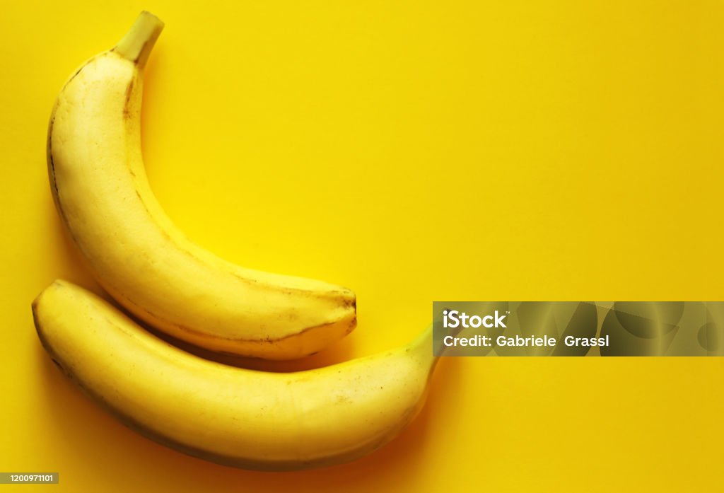 Two Bananas Lying Side By Side On A Yellow Background Stock Photo ...
