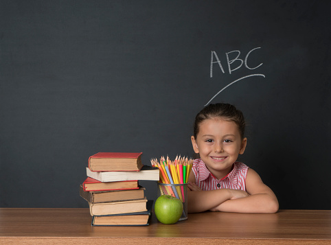 Smiling confident preschooler in front of blackboard