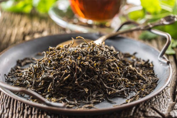 istock Dried tea leaves in bowl on rustic wooden table 1200972838