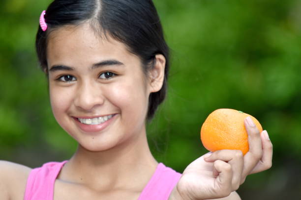istock Smiling Cute Minority Girl With Oranges 1200973523