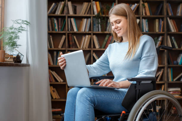 Young woman sitting in a wheelchair disability concept using laptop stock photo