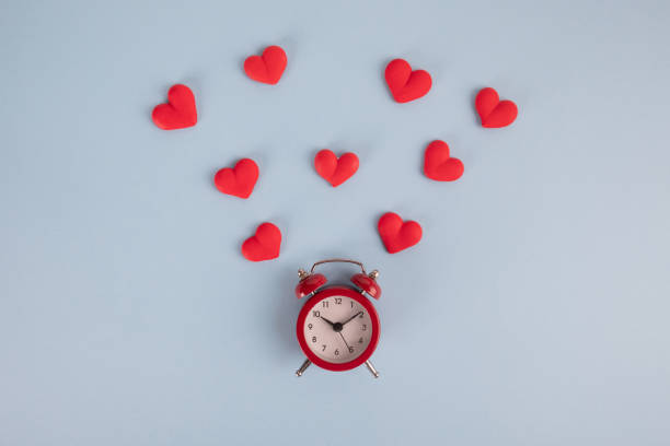 istock Valentine's Day background. Red alarm clock and red hearts around it on a blue background. Time for love. 1200974830