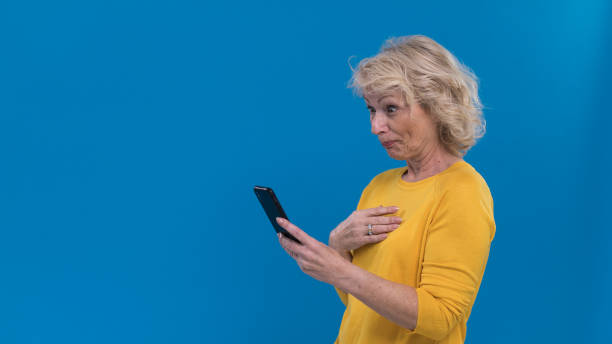 retrato de mujer mayor sorprendida mirando su teléfono inteligente - portrait senior adult confusion women fotografías e imágenes de stock