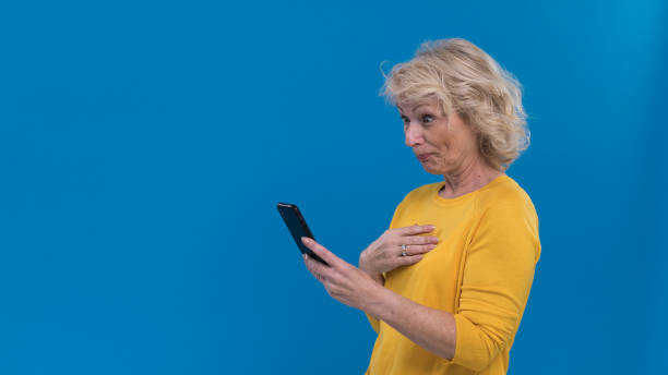 портрет удивленной старшей женщины, смотряной на ее смартфон - portrait senior adult confusion women стоковые фото и изображения