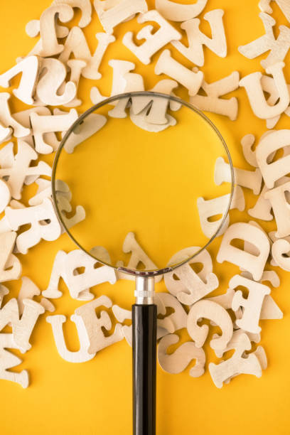 istock Magnifying With Wooden Alphabets Around On Yellow Background 1200976781