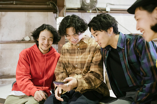 Group of Asian skateboarders watching skateboarding video from a smartphone.