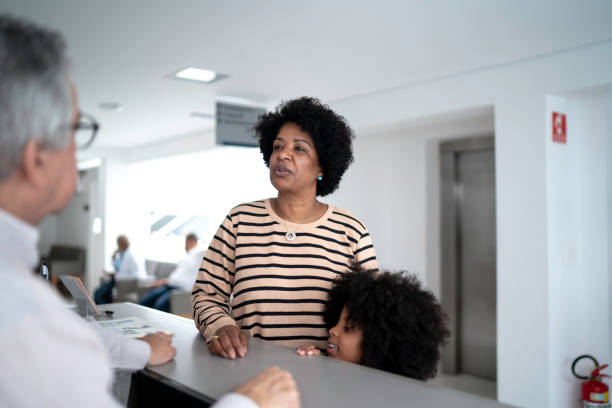 mother and daughter arriving at hospital - doctor patient greeting talking imagens e fotografias de stock