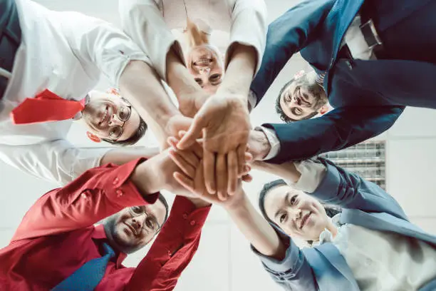 Team of diverse business people stacking their hands together, seen from below