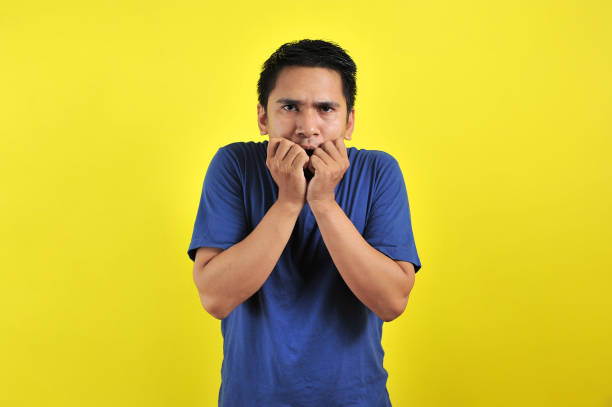 istock Handsome young man looking afraid, stressed and nervous with hands on mouth biting nails 1200979638