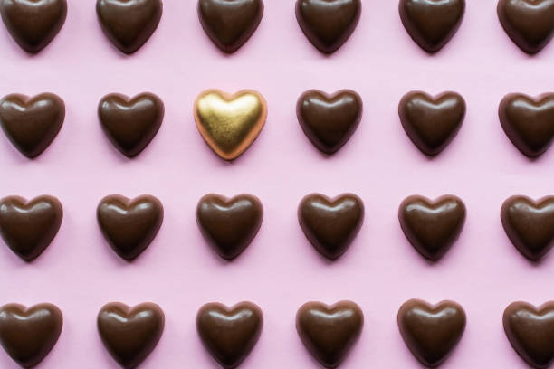 Flat lay with chocolate hearts featuring one yellow gold candy standing out.