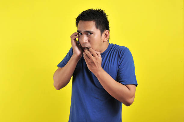 istock Handsome young man looking afraid, stressed and nervous with hands on mouth biting nails 1200980803