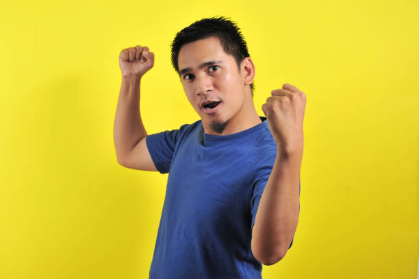 istock Young asian man happy and excited expressing winning gesture 1200982221