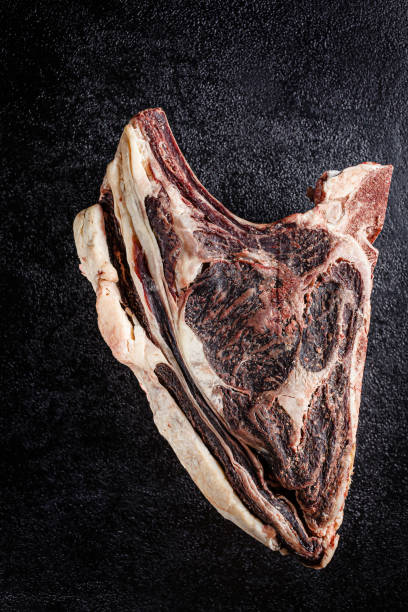 modern kitchen. dry aged beef, veal meat with red pepper and rosemary lies on a black background. board background image, copy space text, top view - scotch steak imagens e fotografias de stock