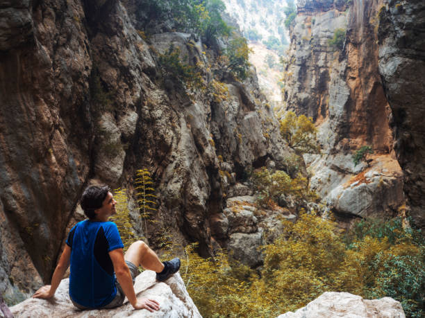 istock young man climbed a rock, trekking in a gorge. Unity with nature 1200987595