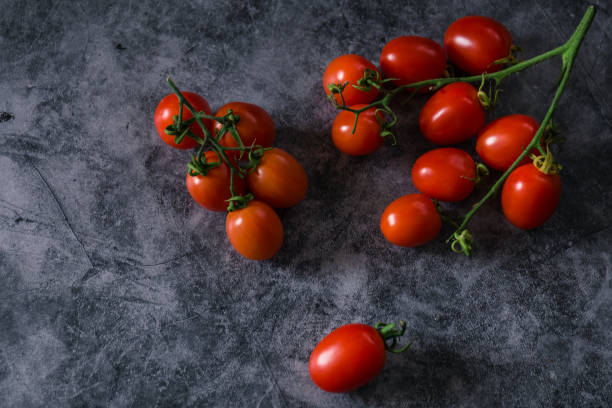 istock fresh tasty cherry tomatoes on dark stone background with copy space 1200988273