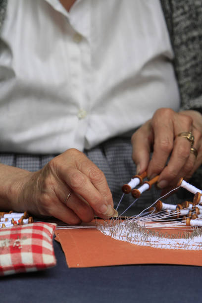 Lacemaker using spools of thread to make a placemat. Bruges. Belgium. Belgium. West Flanders. Bruges. 01/15/2016. This colorful image depicts a lacemaker using spools of thread to make a placemat. lacemaking photos stock pictures, royalty-free photos & images