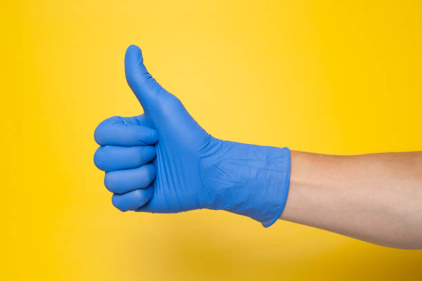 istock Hand in blue glove isolated on yellow with thumb up. 1200989878