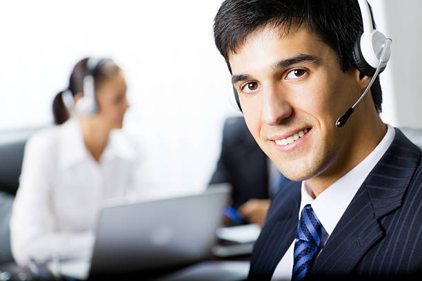 Two people with telephone headsets at workplace stock photo