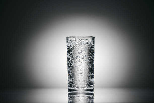 un bicchiere di acqua frizzante su sfondo scuro - soda bottle foto e immagini stock