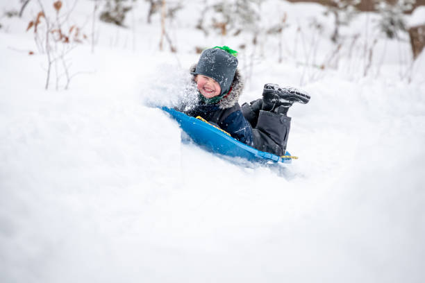 istock Little Boy Sliding in the Snow Outdoors in Winter 1200996608