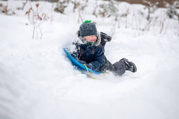 istock Little Boy Sliding in the Snow Outdoors in Winter 1200997485