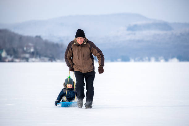 istock Grandfather Pulling Grandson on Sled on Frozen Lake in Winter 1200997717