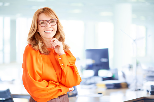 Portrait shot of executive businesswoman with toothy smile standing in the office.