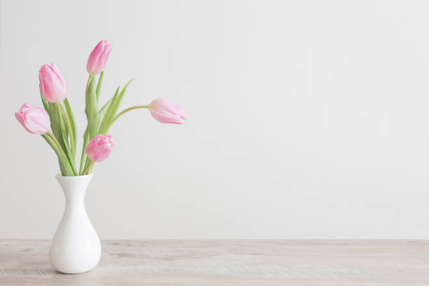 istock pink tulips in white ceramic vase on wooden table on background white wall 1201000261
