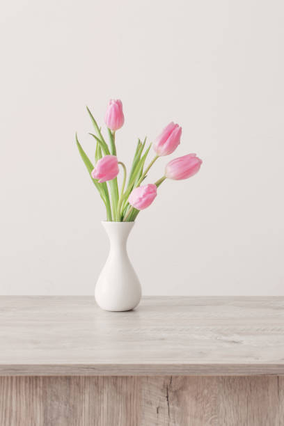 istock pink tulips in white ceramic vase on wooden table on background white wall 1201000285