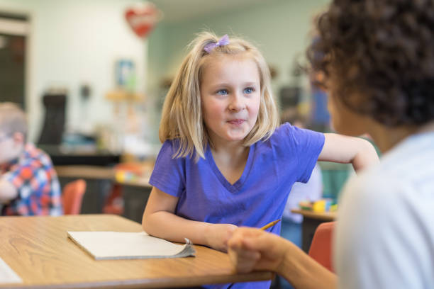 istock First grade girl talking with her teacher in the classroom 1201002523
