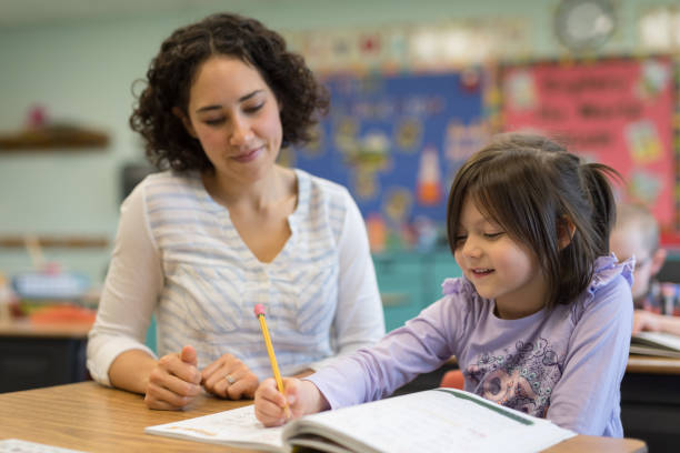 istock First grade girl talking with her teacher in the classroom 1201002531